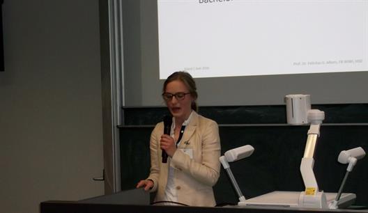 Man sieht Frau Céline Fabienne Lücken, Absolventin des BKM Studiengangs und Gewinnerin des GDD-Wissenschaftspreises, die in ein Mikrophon spricht.
